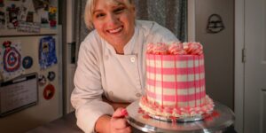 a woman in a chef's uniform is holding a cake